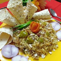 A picture of Capsicum dry fruits pulav with roasted papad and onion salad.