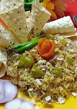 A picture of Capsicum dry fruits pulav with roasted papad and onion salad.