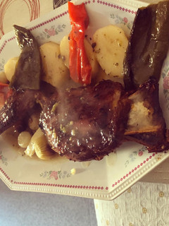 Una foto de Paletilla de cabrito al horno con patatas panaderas y pimientos