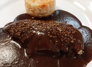 Una foto de Mole poblano con arroz rojo (Puebla)