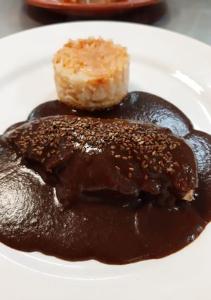 Una foto de Mole poblano con arroz rojo (Puebla)