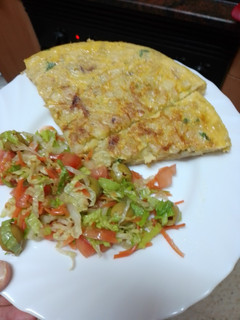 Una foto de Tortilla de papas con cebolla sofrita y perejil picado y ensalada