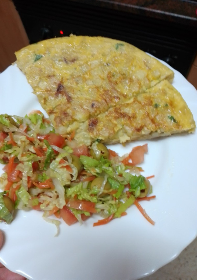 Una foto de Tortilla de papas con cebolla sofrita y perejil picado y ensalada