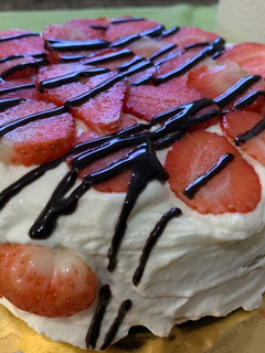 Una foto de Tarta de bizcocho con nata montada, fresas y chocolate
