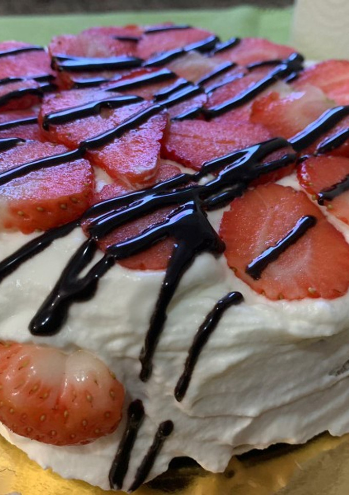 Una foto de Tarta de bizcocho con nata montada, fresas y chocolate