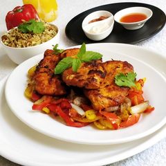 A picture of Pan Fried Chicken Breast on a bed of Pepper's and Onion.
