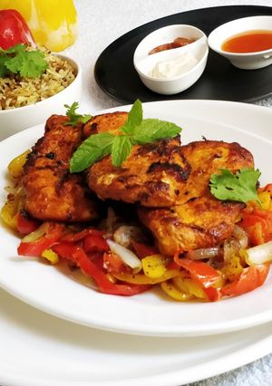 A picture of Pan Fried Chicken Breast on a bed of Pepper's and Onion.