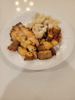A picture of Roasted potatoes and white fish.