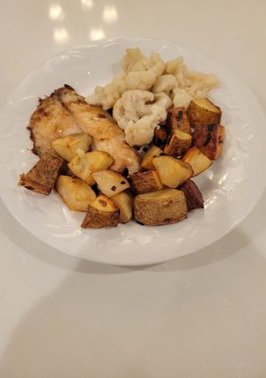 A picture of Roasted potatoes and white fish.