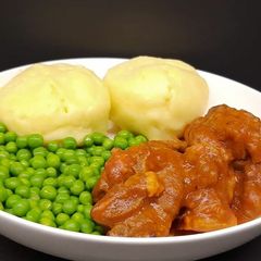 A picture of Lamb neck stew with mashed potatoes, and peas.