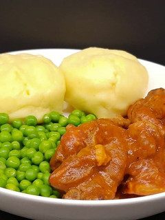 A picture of Lamb neck stew with mashed potatoes, and peas.