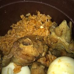 A picture of Title:yummy jollof rice garnished with fried turkey & eggs.