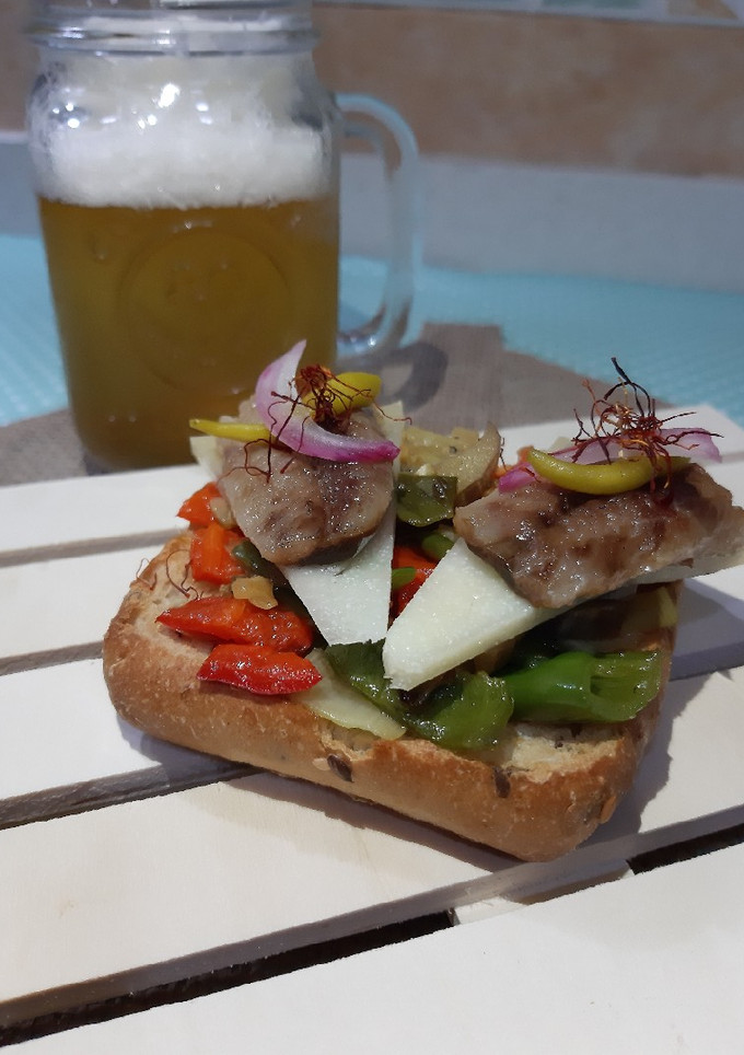 Una foto de Tosta de pan integral sardina ahumada queso ibérico y pimientos