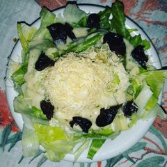 A picture of Salad with Cezarian Dressing,Cheese and Dried Plums.