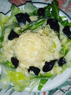 A picture of Salad with Cezarian Dressing,Cheese and Dried Plums.