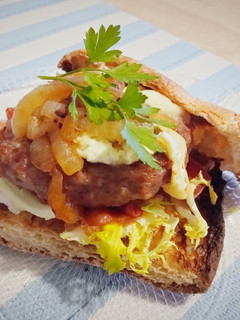 Una foto de Burger (pan de cristal) con crujiente de jamón, escarola y romesco
