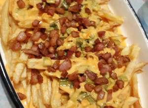 Una foto de Papas con cheddar, bacon y verdeo