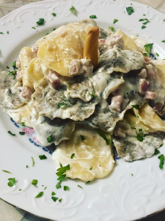 Una foto de Raviolis de huevo y cereales rellenos de parmesano con salsa de crema de leche y dados de bacon