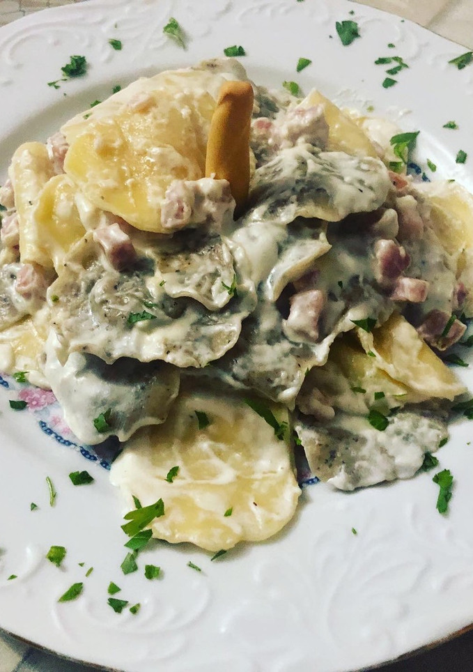 Una foto de Raviolis de huevo y cereales rellenos de parmesano con salsa de crema de leche y dados de bacon