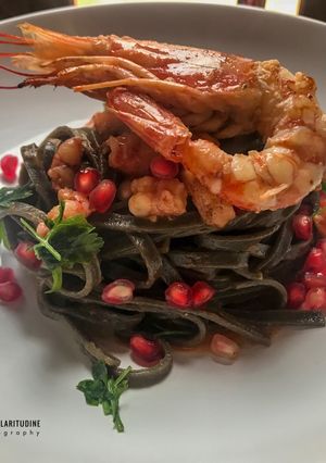 Foto di Tagliolini al nero di seppia con salsa di gambero rosso, melograno e prezzemolo