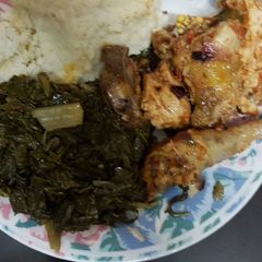 A picture of Ugali served with chicken and spinach.