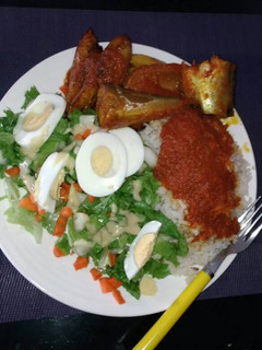 A picture of White rice with stew,Titus fish and salad.