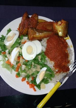 A picture of White rice with stew,Titus fish and salad.