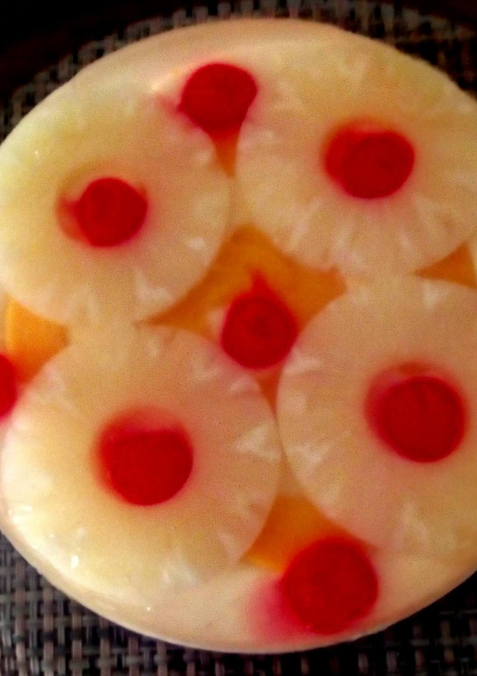 Una foto de Gelatina encapsulada con rodajas de piña, melocotones y cerezas