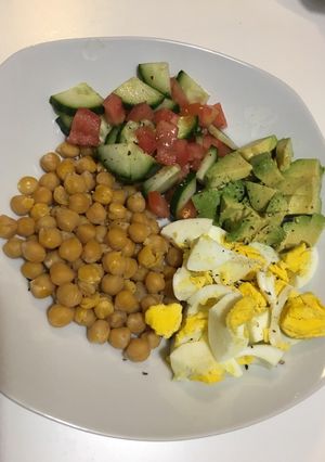 A picture of Chickpeas, boiled eggs, avocado with cucumber & tomatoes.