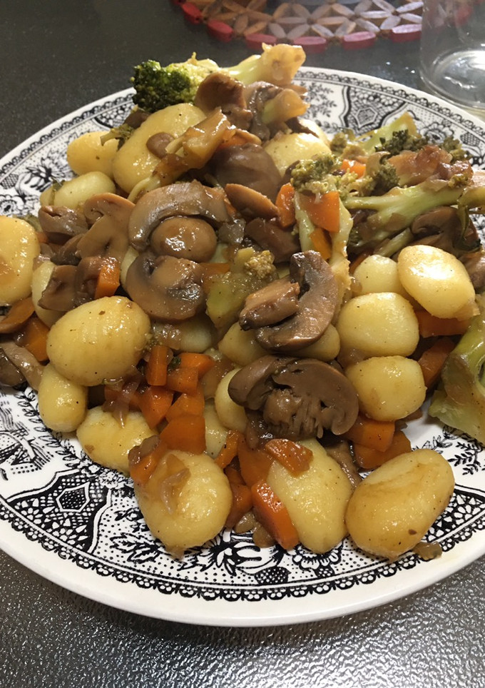 Una foto de Ñoqui salteados con champiñones, zanahorias y brócoli