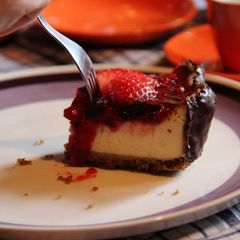 A picture of New York cheesecake w strawberry coulis & dark chocolate border.