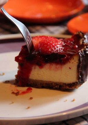 A picture of New York cheesecake w strawberry coulis & dark chocolate border.