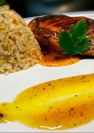 Una foto de Pechuga de pollo en reducción de parchita y arroz con frutos secos