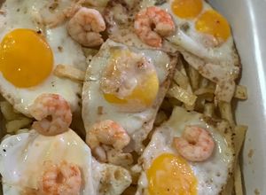 Foto principal de Huevos rotos con langostinos al ajillo y patatas pajas
