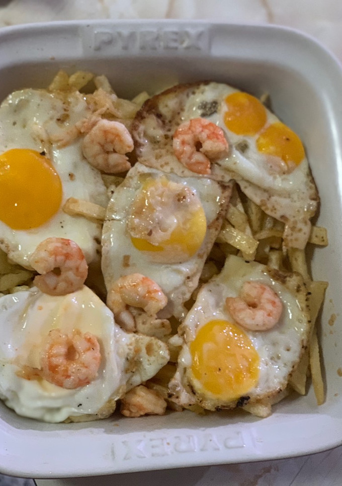 Una foto de Huevos rotos con langostinos al ajillo y patatas pajas