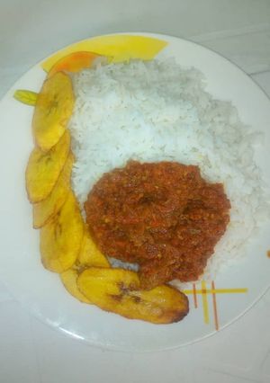 A picture of Rice with sauce and fried plantain.
