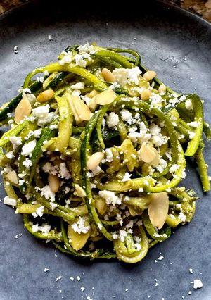 A picture of Zucchini Spaghetti with Basil Pesto, Crumbled Feta, Almonds, and Pine Nuts.