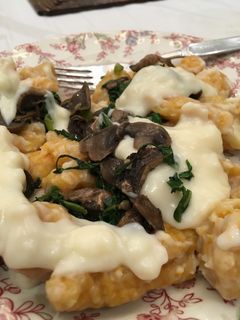 Una foto de Ñoquis con salsa blanca, espinaca y champiñones