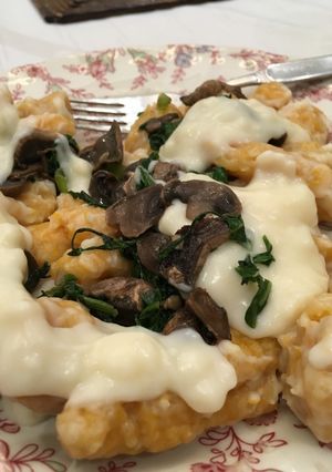 Una foto de Ñoquis con salsa blanca, espinaca y champiñones