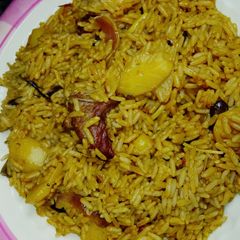 A picture of Jollof rice with potato and meat.