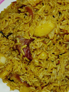 A picture of Jollof rice with potato and meat.