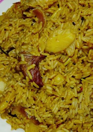 A picture of Jollof rice with potato and meat.