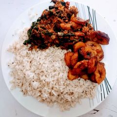 A picture of Ofada rice with fried plantain and vegetable sauce.