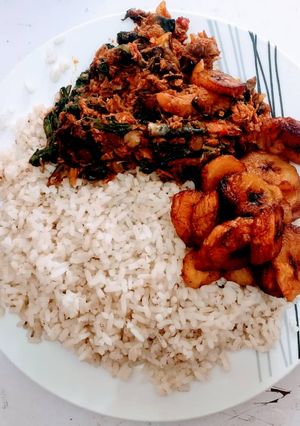 A picture of Ofada rice with fried plantain and vegetable sauce.