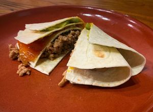 Una foto de Tortilla trend con cerdo teriyaki, cebolla caramelizada, pepinillo encurtido y yema curada soja y PX