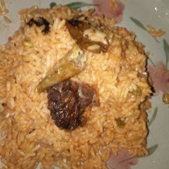 A picture of Jollof rice and fried meat.