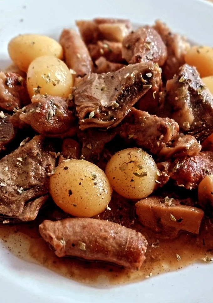 Una foto de Lagarto y salchichas de cerdo con champiñones, patatas y alcachofas