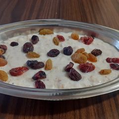 A picture of Oatmeal porridge topped with berries and raisins.