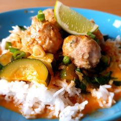 A picture of Chicken meatballs with red curry sauce.