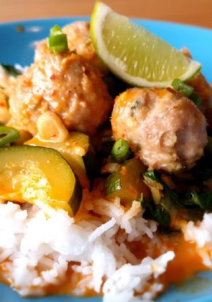 A picture of Chicken meatballs with red curry sauce.